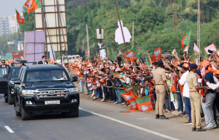 Prime Minister Narendra Modi waves to people during a roadshow, in Surat